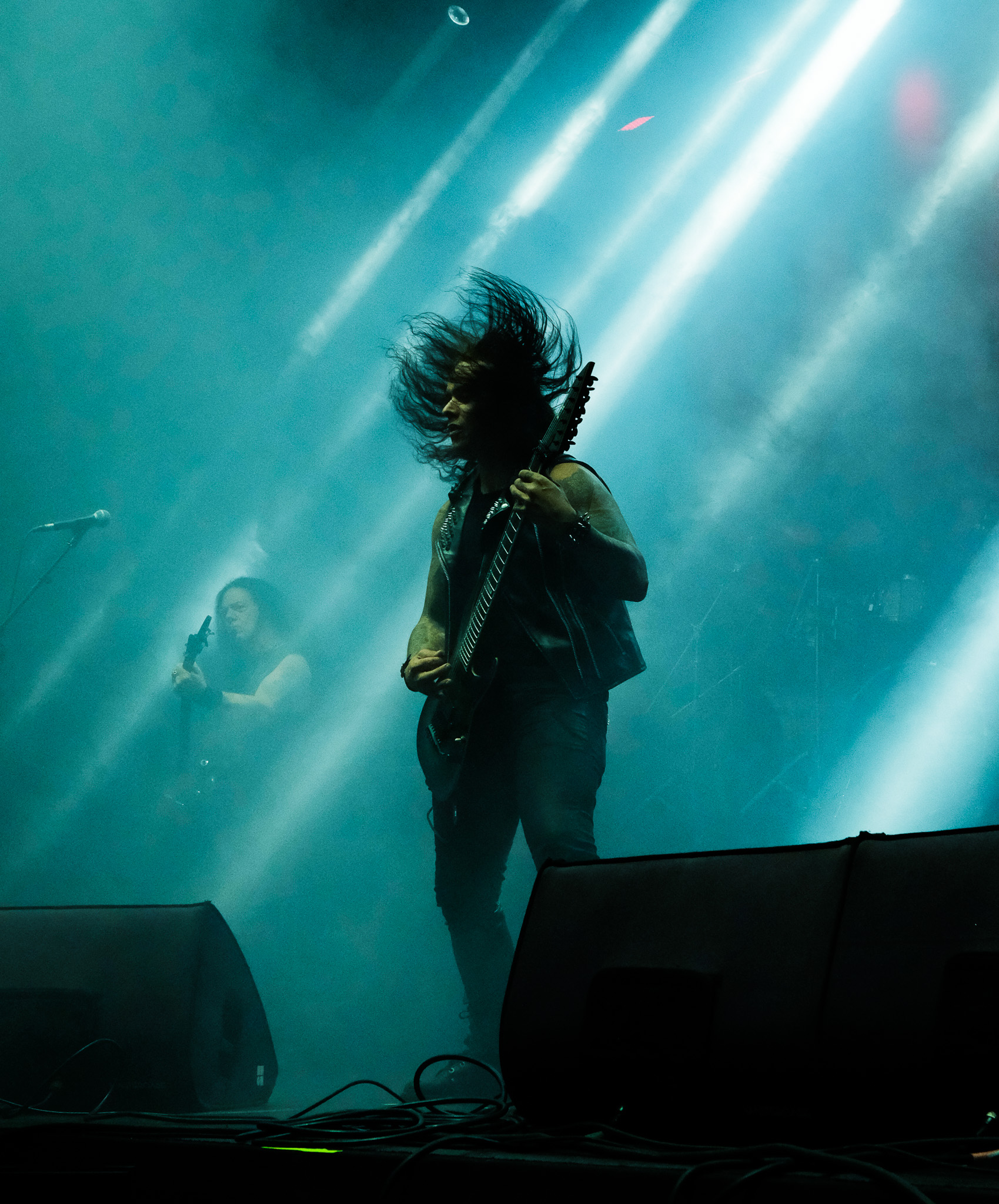 Turkuaz ışıkta sahnede gitar çalan müzisyen
